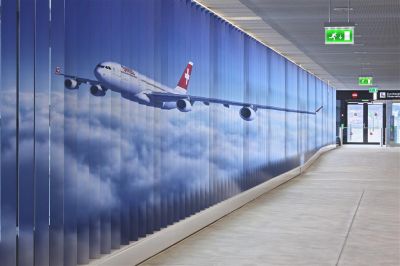 Feststehende Aluminiumlamellen sind die Träger der beiden riesigen Bilder im Zugangskorridor zur neuen Zuschauerterrasse am Dock B des Flughafens Zürich.